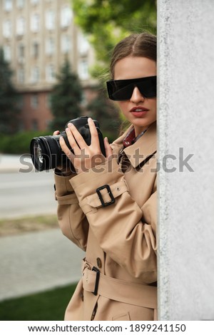 Private detective with modern camera spying on city street