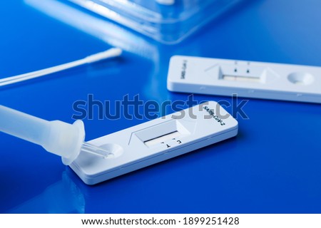 some covid-19 rapid antigen test kits, with the diagnostic test devices and some nasopharyngeal swabs, on a blue surface Royalty-Free Stock Photo #1899251428