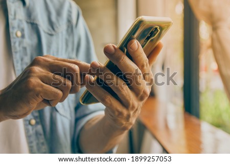 Zoom View Front Right Hand of Casual Businessman Using Smartphone on Blurring Coffee Shop Background in Vintage Tone