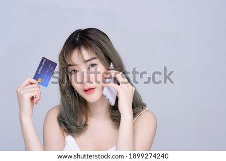 Beautiful woman model posing with credit card and mobile phone portrait isolated on grey background