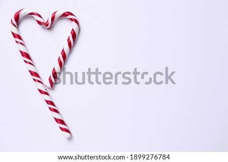 Heart shape made of candy canes on white background, top view