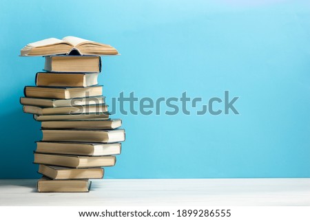 Composition with vintage old hardback books, diary, fanned pages on wooden deck table and red background. Books stacking. Back to school. Copy Space. Education background. Royalty-Free Stock Photo #1899286555