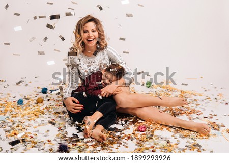 Portrait of a happy mother and son on a white background in confetti.