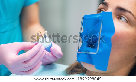 An Endodontist Preparing Barbed Broach for Endodontic Treatment in Dental Clinic. Royalty-Free Stock Photo #1899298045