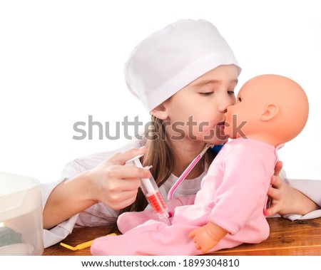 Adorable little girl playing at the doctor examining her doll on a white