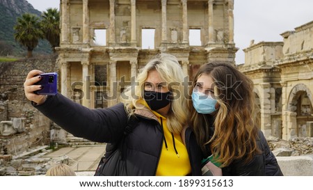 Traveling during the Covid-19 pandemic. A woman in a mask takes a selfie photo against the backdrop of attractions. Ruins of the ancient Greek city of Ephesus in Turkey. Taking pictures of himself.