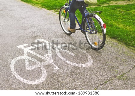 Commuting to work on a bicycle. Woman riding bicycle on a bike path marked with symbol.