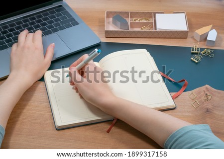 Young woman typing on laptop and make notes stock photo