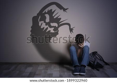 Shadow of monster on wall and scared boy in room Royalty-Free Stock Photo #1899322960
