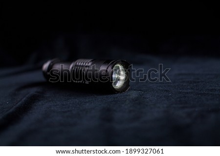 a tactical flashlight on black background shines