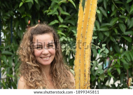 Blonde woman smiling on green and natural background. Brazilian with green eyes posing for photo. Natural lifestyle. Smiling girl. Girl posing for photos in nature. Selective focus.