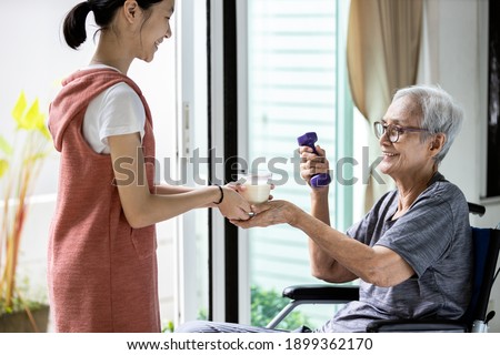 Asian child girl hold a glass of warm milk,taking care of senior woman,giving fresh milk or nutritional supplements in the morning during exercise,drinks of the old elderly,food necessary for health