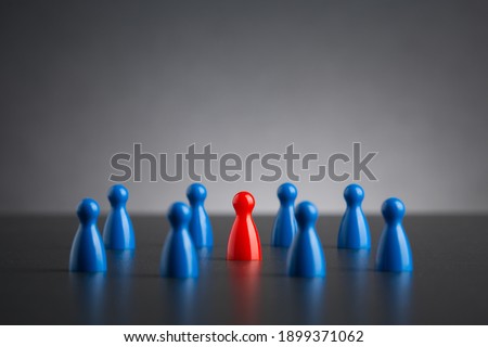 Selective focus on single red figure among blue group