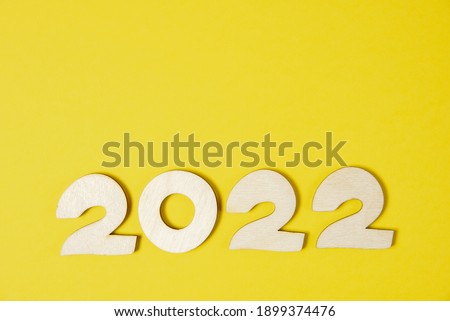 Wooden numbers 2022 on a yellow paper background close-up. Trendy new year template for design with place for text