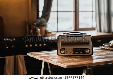 The FM channel is playing music, a stylish retro radio player stands on a wooden table. stylish kitchen in the village, daylight from the window. copy space Royalty-Free Stock Photo #1899377164