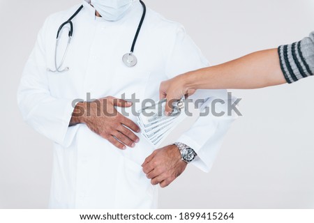 Medic takes bribe. Close up particle view of young man that standing indoors against white background.