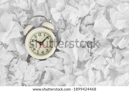 Vintage alarm clock on white crumpled paper background with copy space. Top view	