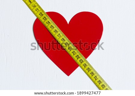 a red heart crossed by yellow centimeter on white background