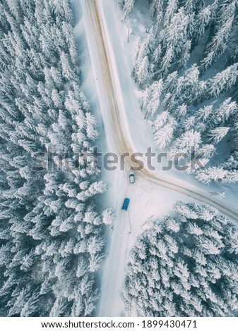 Cars driving on a beautiful mountain road on snow. Aerial view.