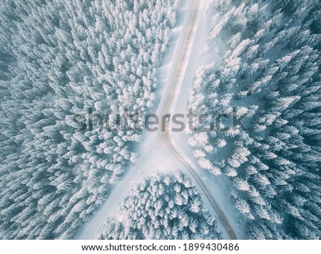 Cars driving on a beautiful mountain road on snow. Aerial view.