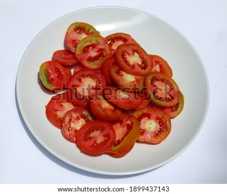 Tomatoes on a white plate, isolated on a neutral background.
					