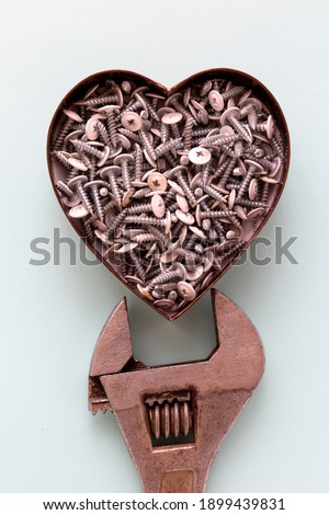 The heart full of metal screws with a fixing wrench. Male gift for Valentine's day