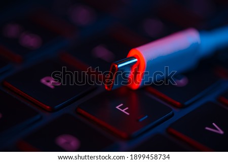 Macro shot view of USB switch on a laptop keyboard with neon lights. Close-up view. Concept of modern technology.