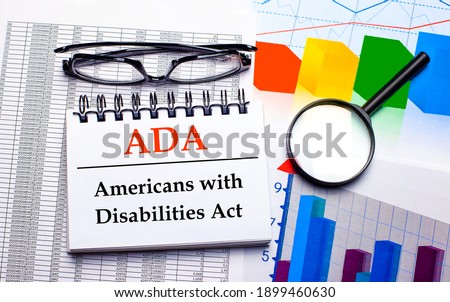 Glasses, magnifier, color charts and a white notepad with text ADA on the desktop. Business concept. View from above
