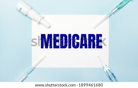 On a blue background, syringes, a vial of medicine, an ampoule and a white sheet of paper with the text MEDICARE. Medical concept
