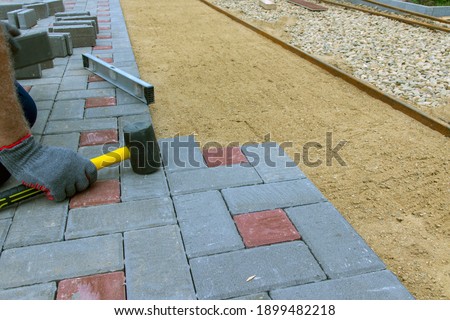 The craftsman installs and lays paving stones on the terrace, road or sidewalk. A worker uses stones to build a sidewalk. Selective focus.