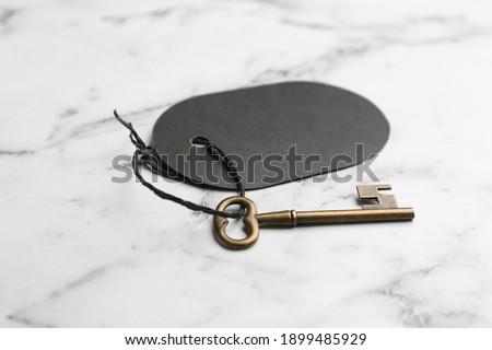 Vintage key with blank tag on white marble table. Keyword concept