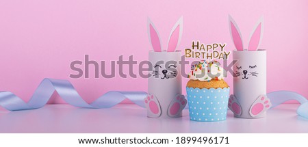 Cute paper rabbits from a roll of toilet paper with the cake on his birthday. Background for the birthday party. children's holiday