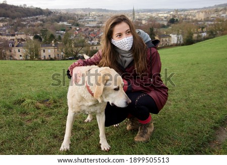 Coronavirus. Woman with face mask takes her dog for a walk during coronavirus. Short walks during coronavirus. Quarantine with a dog.  Royalty-Free Stock Photo #1899505513