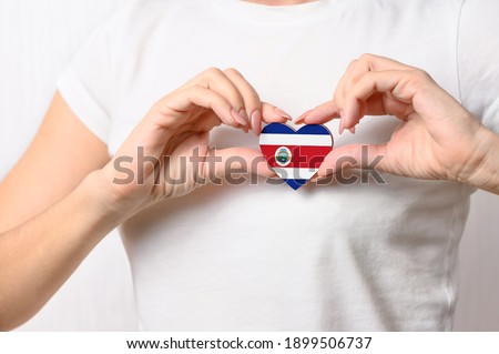 Love Costa Rica. The girl holds a heart in the form of the flag of Costa Rica on her chest. Costa Rican Patriotism concept
