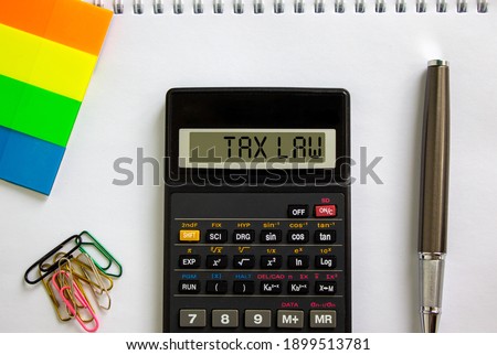 Tax law symbol. Calculator with words 'Tax law', white note, colored paper, paper clips, pen. Beautiful white background. Business and tax law concept.