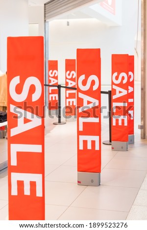 Inscription Sale on the background of a red glass wall in the store. Mall Discount Announcement. Summer, winter Christmas, New Year sale.Sale red sign at mall. Lifestyle promotion. Retail commercial