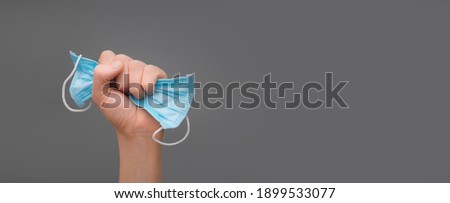 Recovery from illness after covid-19 pandemic end raised hand holding face mask. Quarantine is over banner and mask in fist as sign fight to virus and new normal with victory hand or stop coronavirus Royalty-Free Stock Photo #1899533077