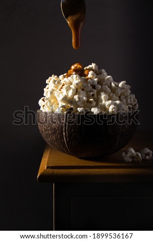 popcorn in coconut bowl with caramel drizzle. pour dark food photography