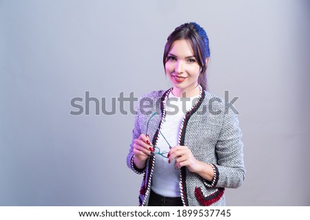 Business woman holding glasses in her hands on modern studio background with neon lighting.
