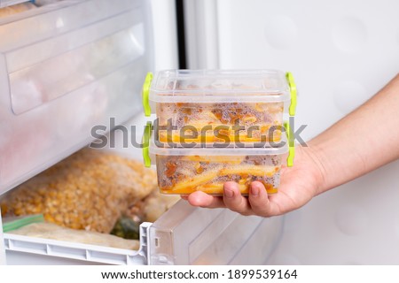 Ready frozen meal in a container in the refrigerator. Frozen food in the freezer. Fast cooking concept Royalty-Free Stock Photo #1899539164