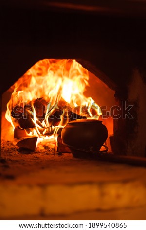 Firewood is burning in the stove. Open fire. Warmth and comfort in the house. Soup in a cast iron pot. Oven in the village. 