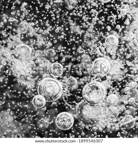 A closeup black and white photograph of medium and small ice bubbles