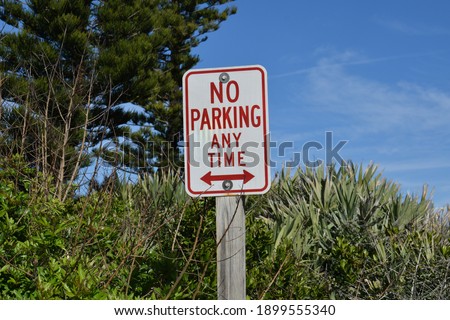 A no parking sign attached to a wooden post.