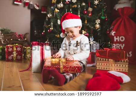 young girl sit on floor and open Christmas gift box at home