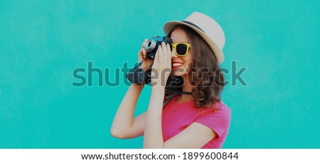 Summer portrait of young woman photographer with vintage film camera on a blue background