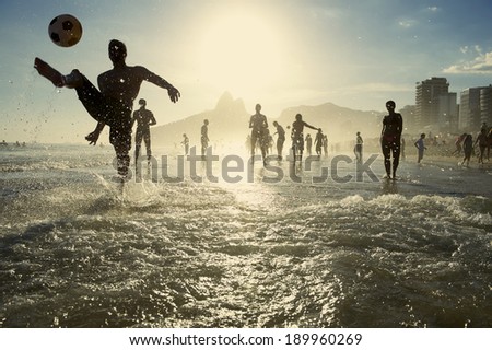Carioca Brazilians playing altinho beach football in silhouettes kicking soccer balls in the waves of Ipanema Beach Rio de Janeiro Brazil