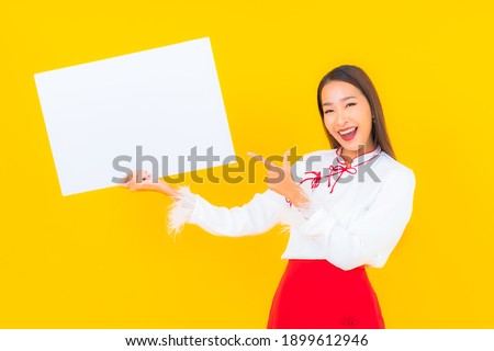 Portrait beautiful young asian woman show white empty billboard on yellow isolated background