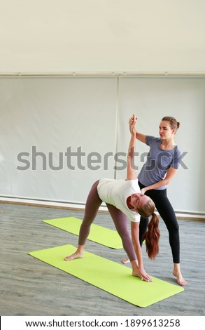 Image picture yoga coach helps beginner to make stretching exercises. Teacher assists to make position pose. Healthy lifestyle in fitness class. sporty people practicing in studio, working out indoor.