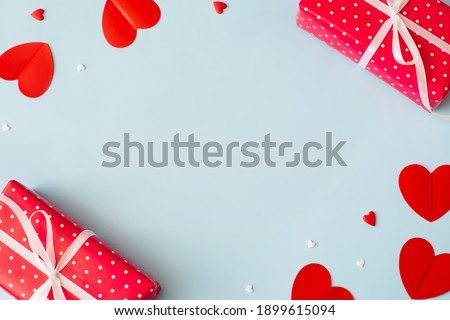 Valentine's Day background February 14th. Gifts, confetti, red hearts of paper on pastel blue background. Valentines day concept. Flat lay, top view, copy space.