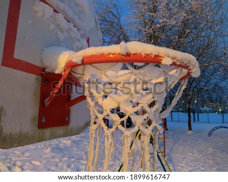 basketball hoop covered with snow at night